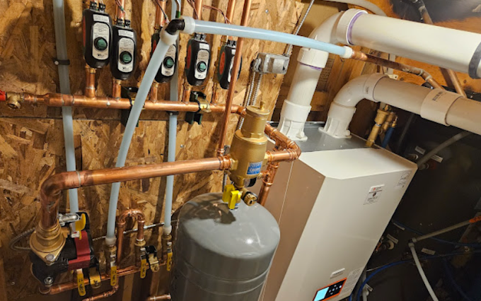 A boiler is being installed in a basement with copper pipes.