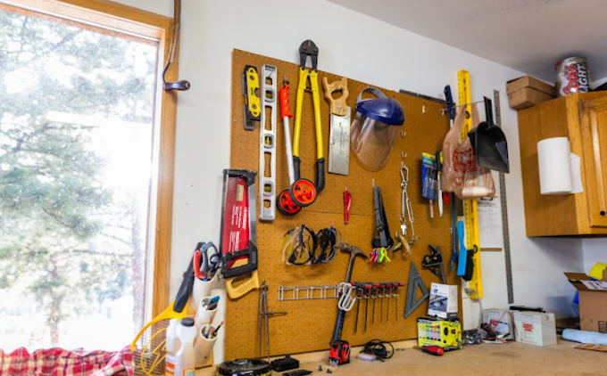A bunch of tools are hanging on a wall in a garage.