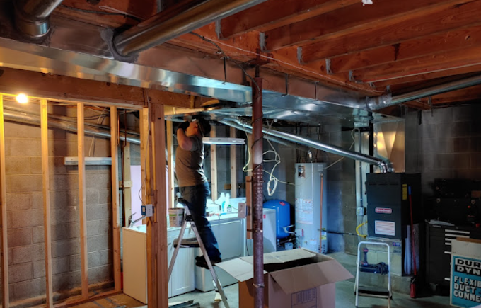 A man is standing on a ladder in a basement.
