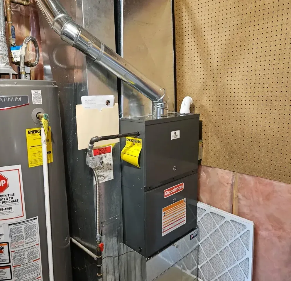 A water heater is sitting next to a furnace in a basement.