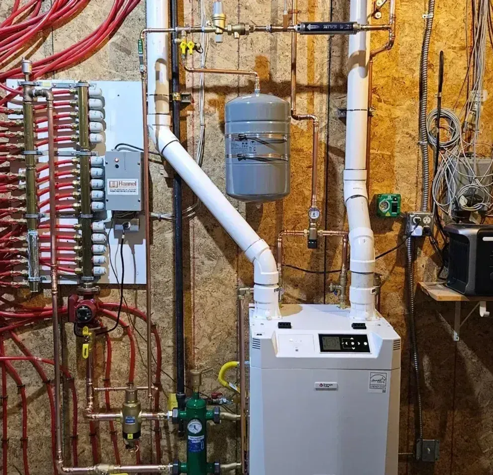 A blue water heater is sitting in a basement next to a boiler.