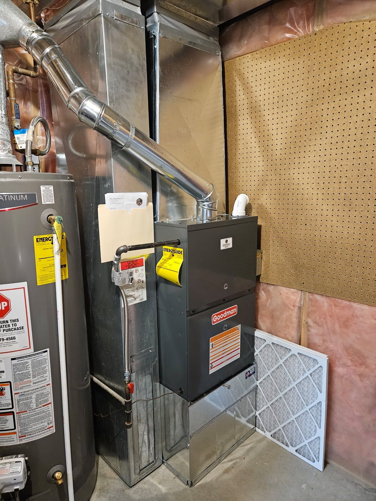 A boiler is being installed in a basement with copper pipes.