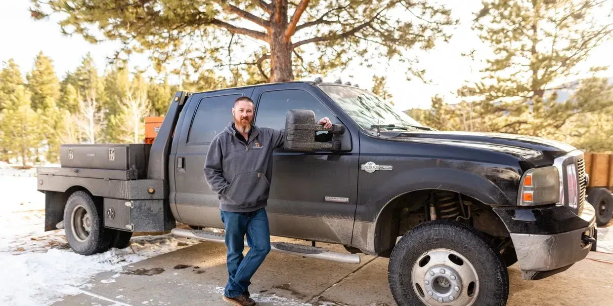 A man is standing next to a truck in the snow.