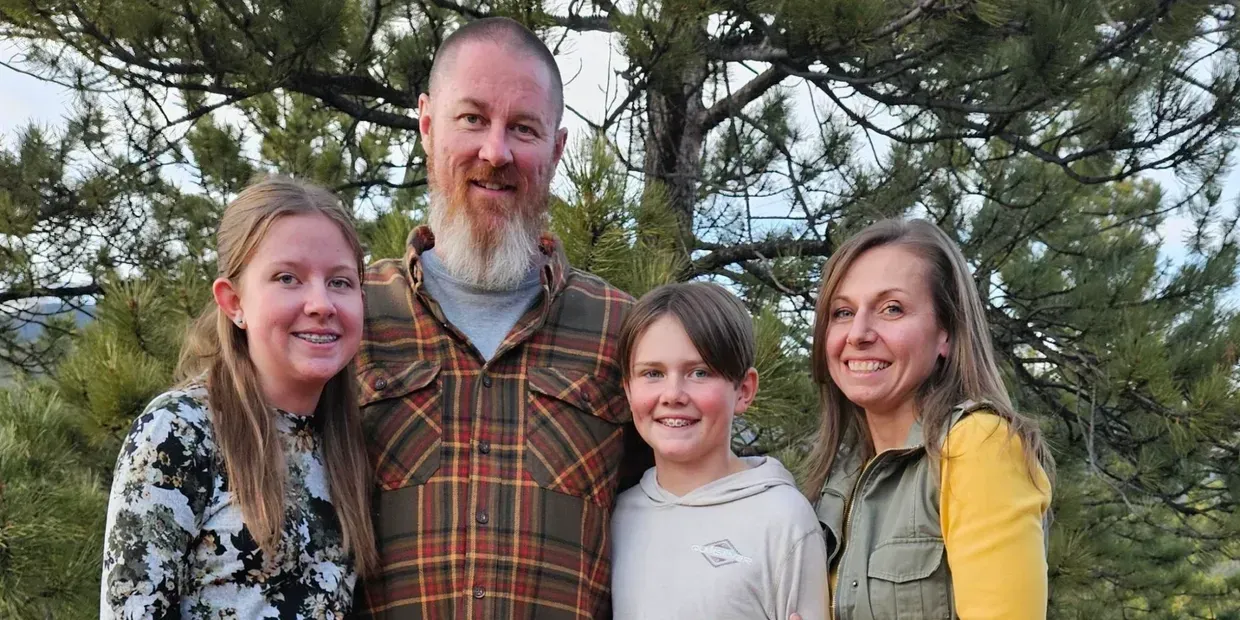 A family is posing for a picture in front of a tree.