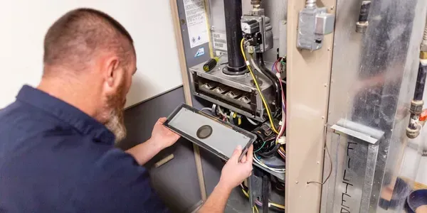 A man is working on a heating system with a tablet.