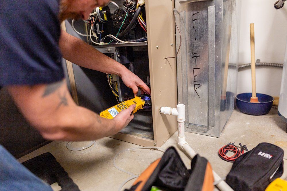 A man is working on an air conditioner in a basement.
