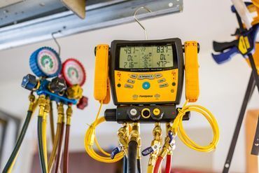 A bunch of hose and gauges are hanging from the ceiling.