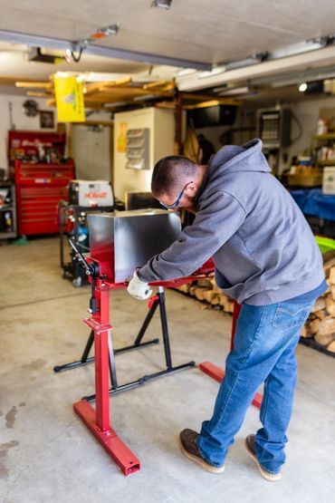 A man is working on a piece of metal in a garage.