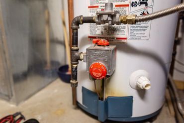 A water heater is sitting on the floor in a basement.