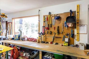 A workbench in a garage filled with tools and a window.