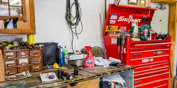 A workbench in a garage with a red snap on toolbox.