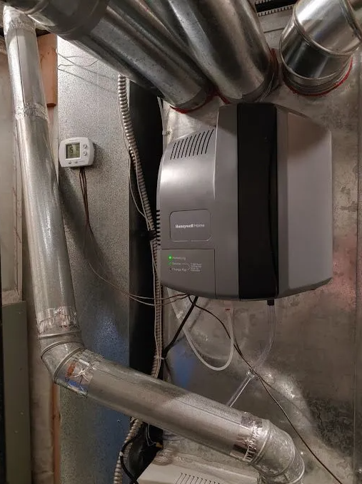 A humidifier is sitting on top of a metal box in a basement.