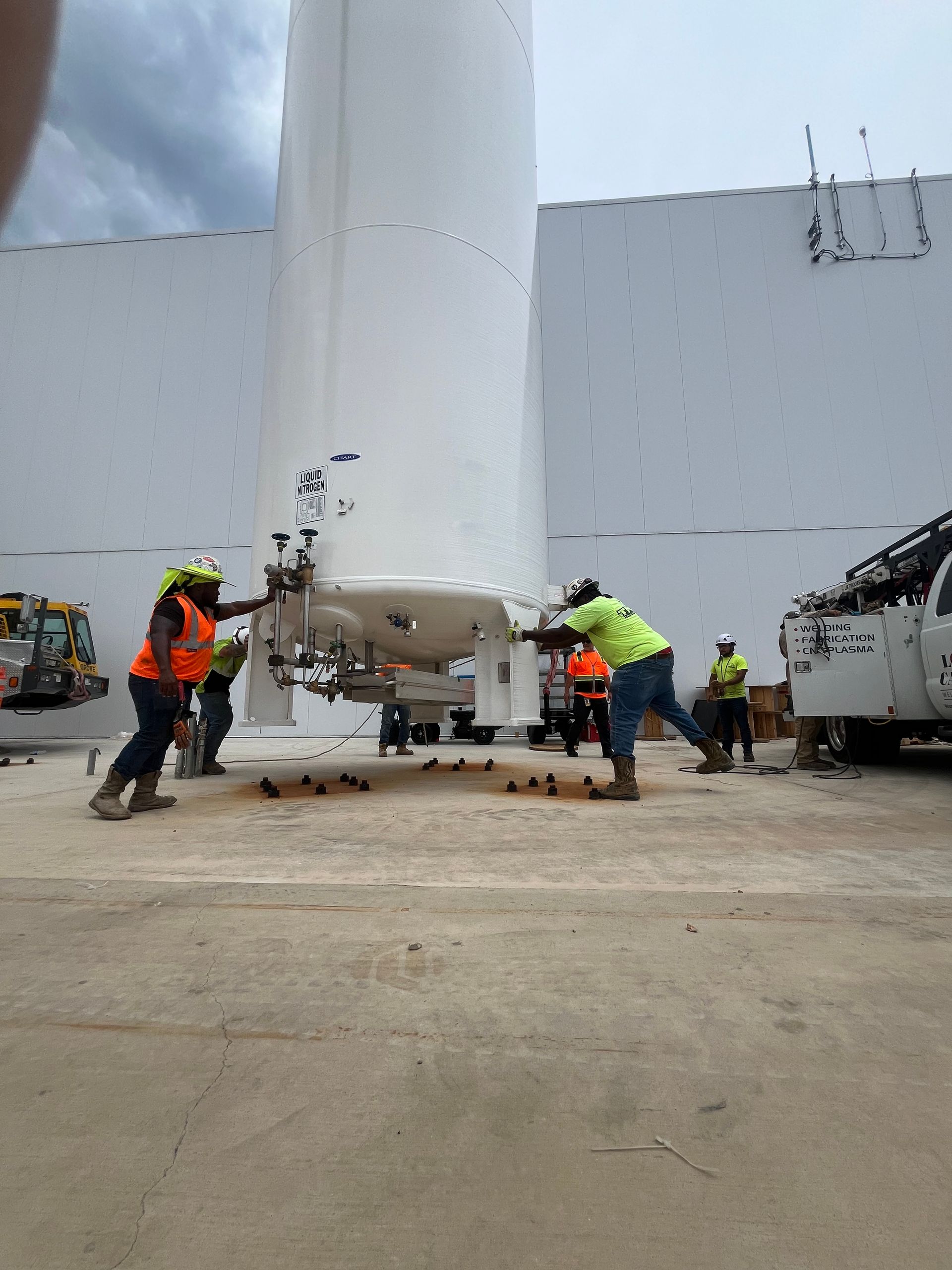 A group of construction workers are working on a large tank.