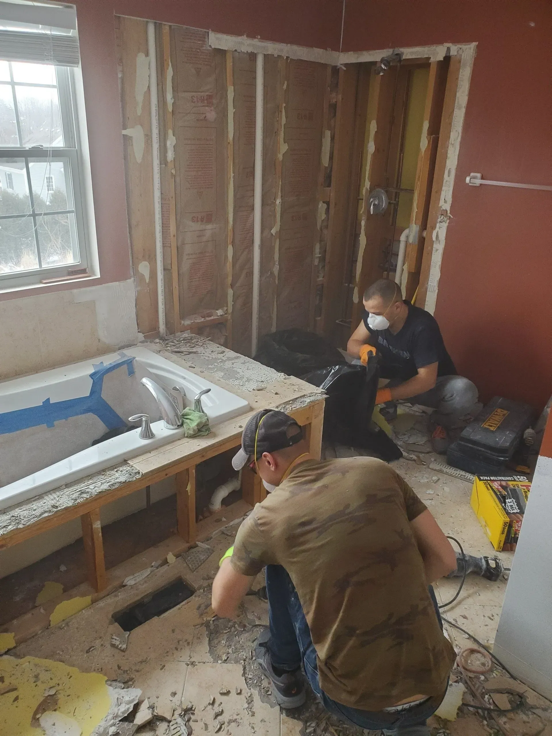 Two men are working on a bathtub in a bathroom.