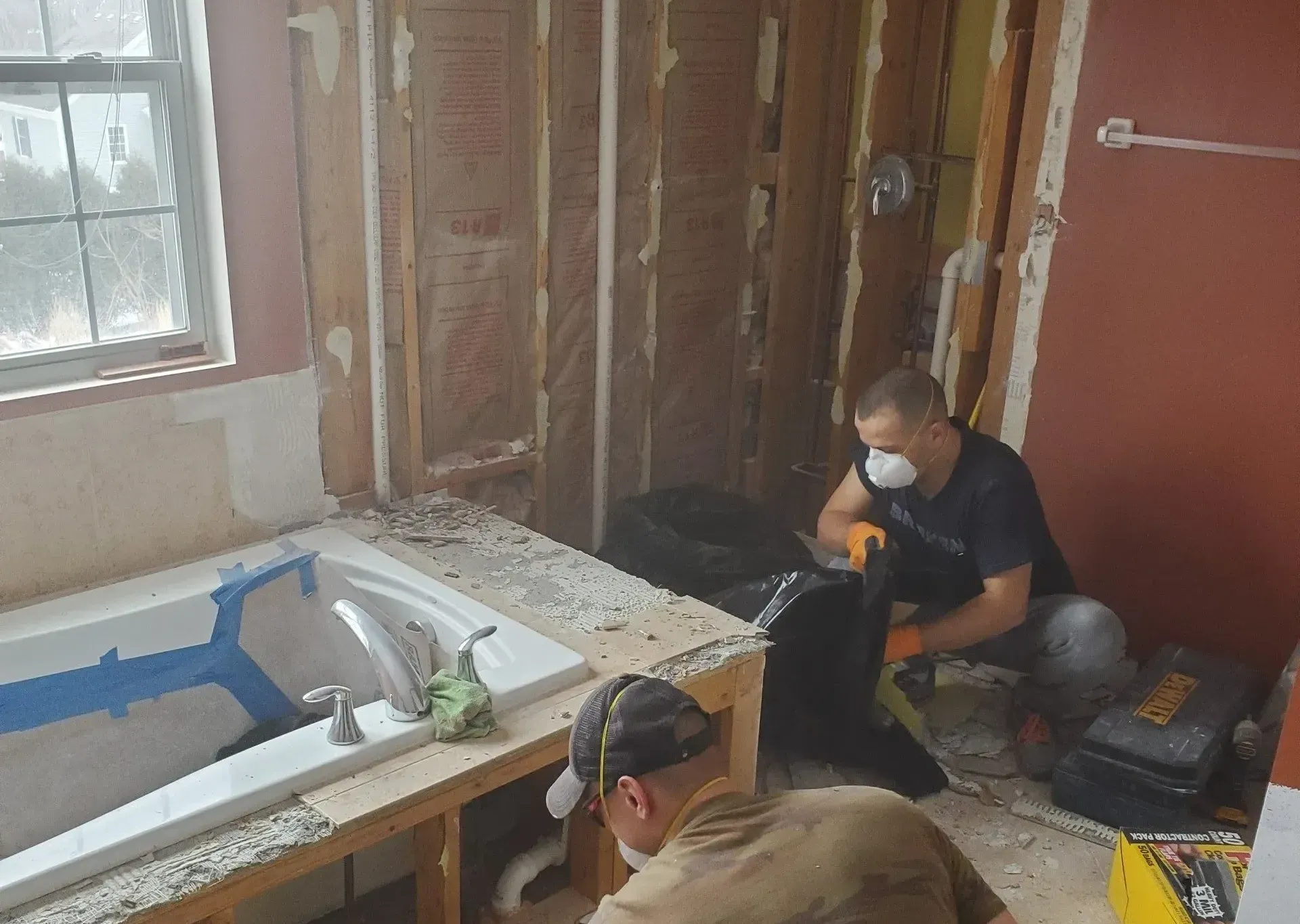 Two men are working on a bathtub in a bathroom.