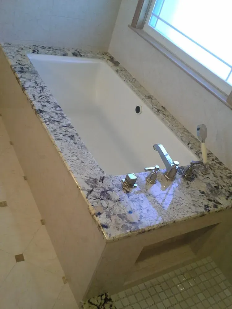 A bathtub with a granite counter top in a bathroom