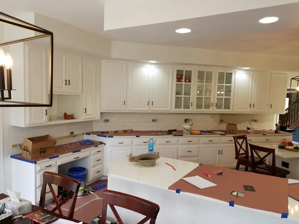 A kitchen is being remodeled with white cabinets and granite counter tops.