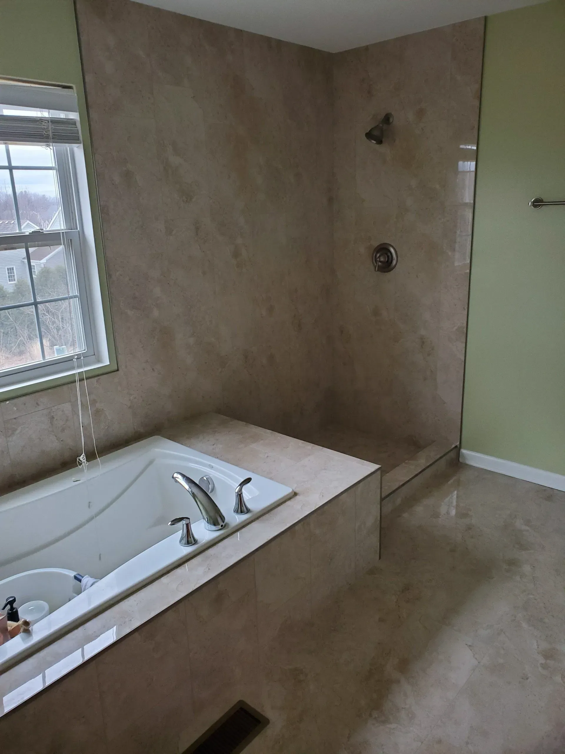 A bathroom with a tub , shower and window.