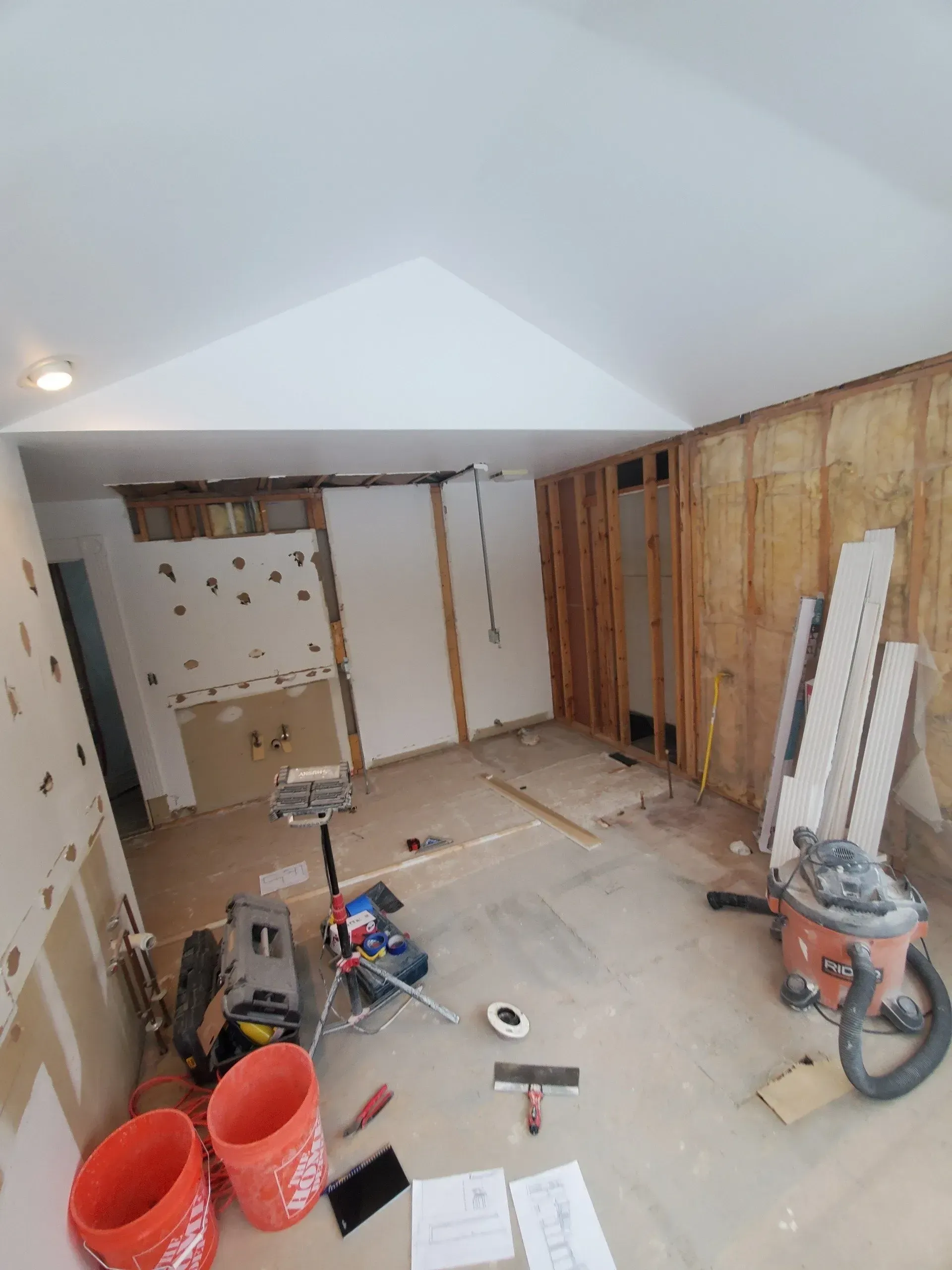A room that is being remodeled with tools and buckets on the floor.
