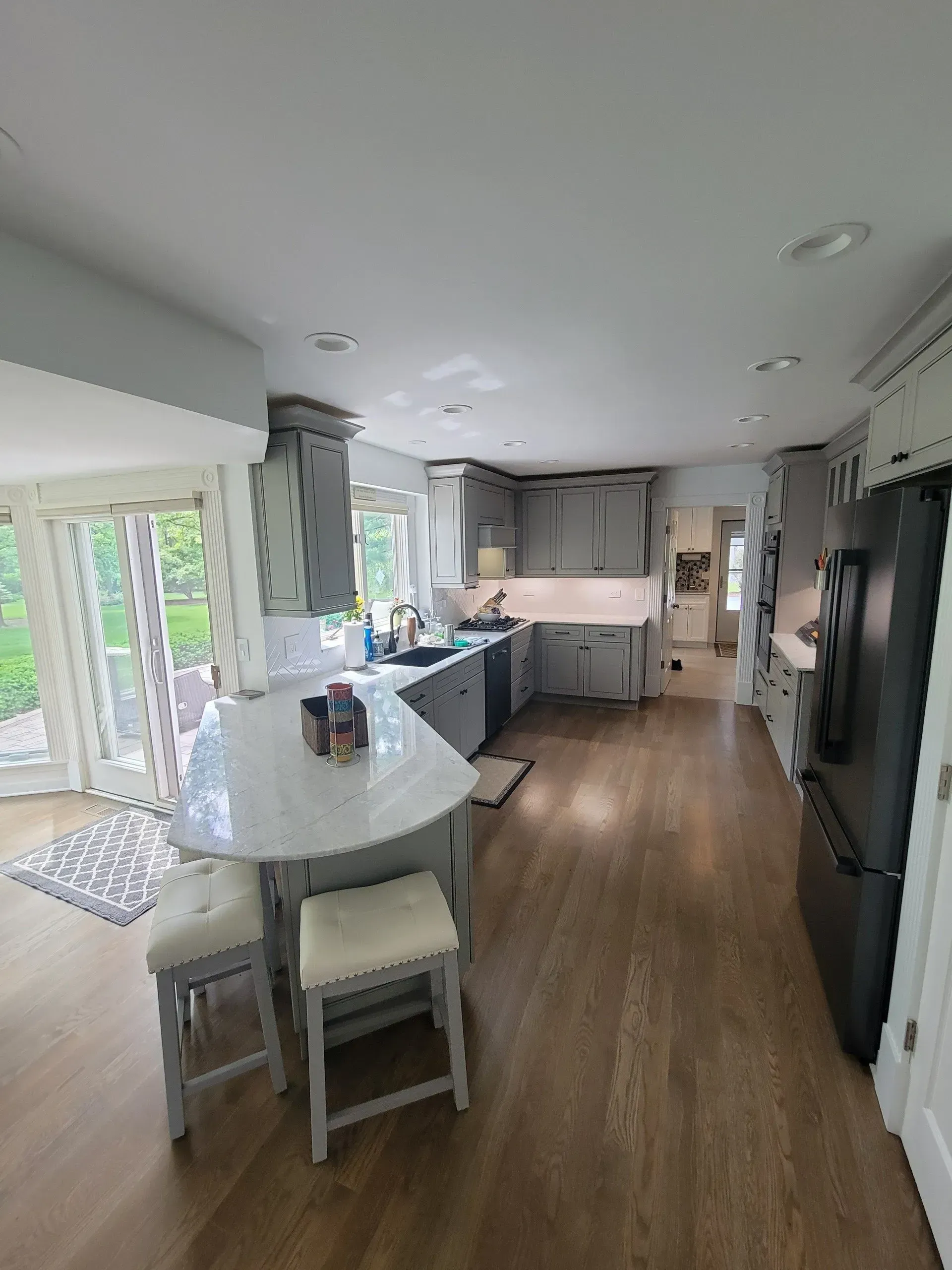 A kitchen with a large island , stools , and a refrigerator.