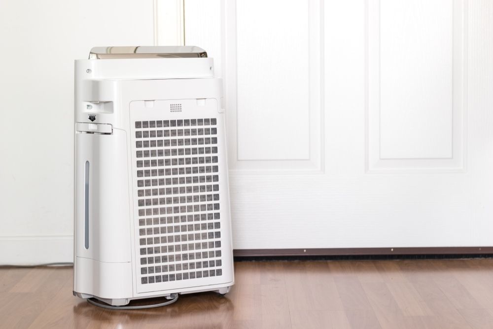 A White Air Purifier is Sitting on a Wooden Floor Next to a Door — Airac Sales & Service in Berserker, QLD
