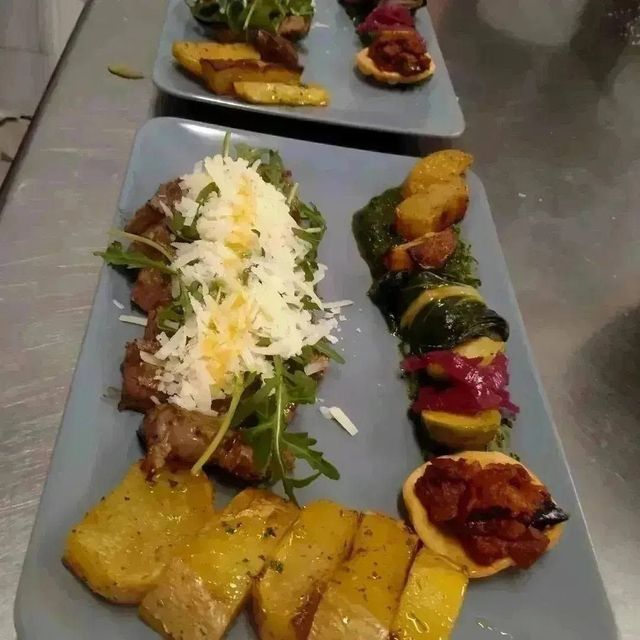 Antipasti serviti su piatti rettangolari grigi, completi di spiedini, guarnizione e verdure arrostate colorate.