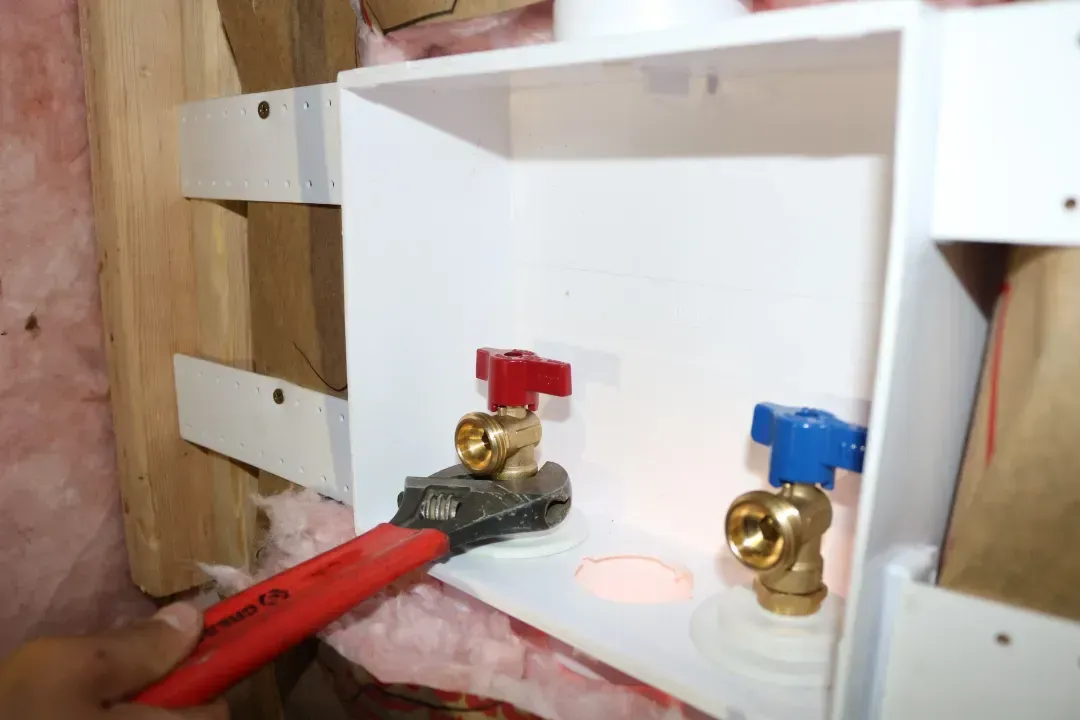 A person is using a pair of pliers to remove a valve from a box.