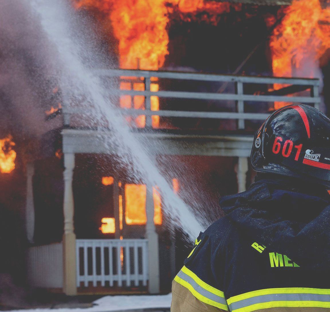 New York brick walkup on fire, fire fighters spraying it with water