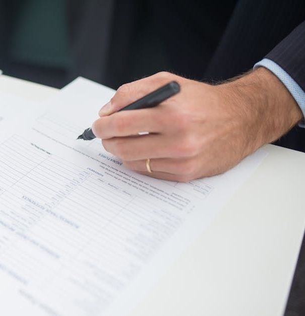 Person's hand signing paperwork