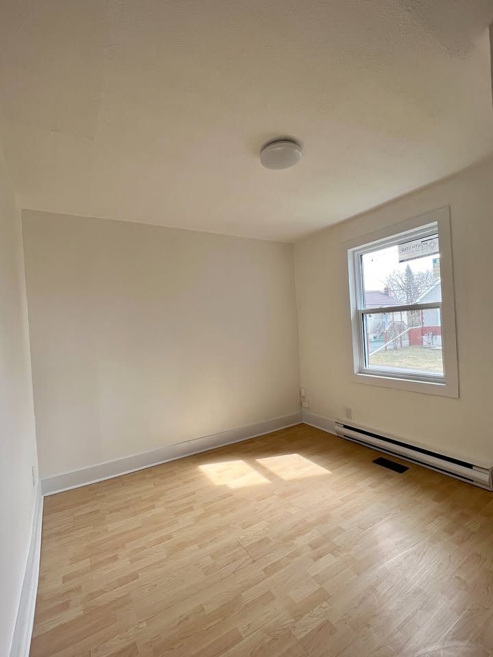 An empty room with hardwood floors and a window.