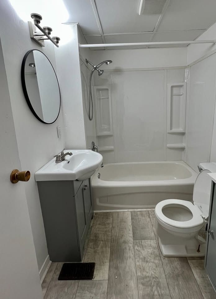 A bathroom with a sink , toilet , bathtub and mirror.