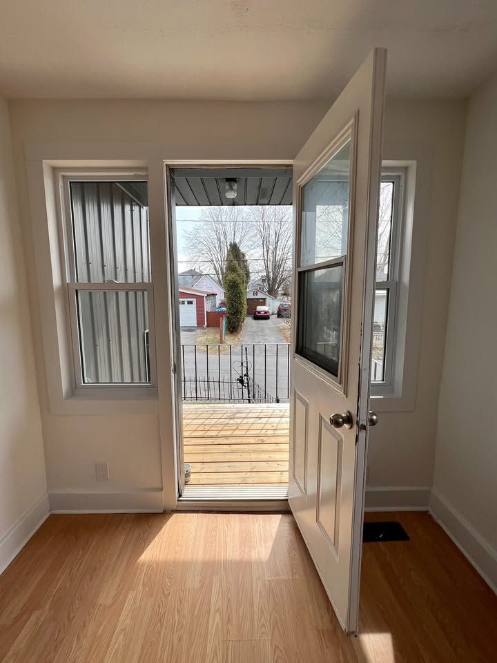 An empty room with a door open to a balcony.