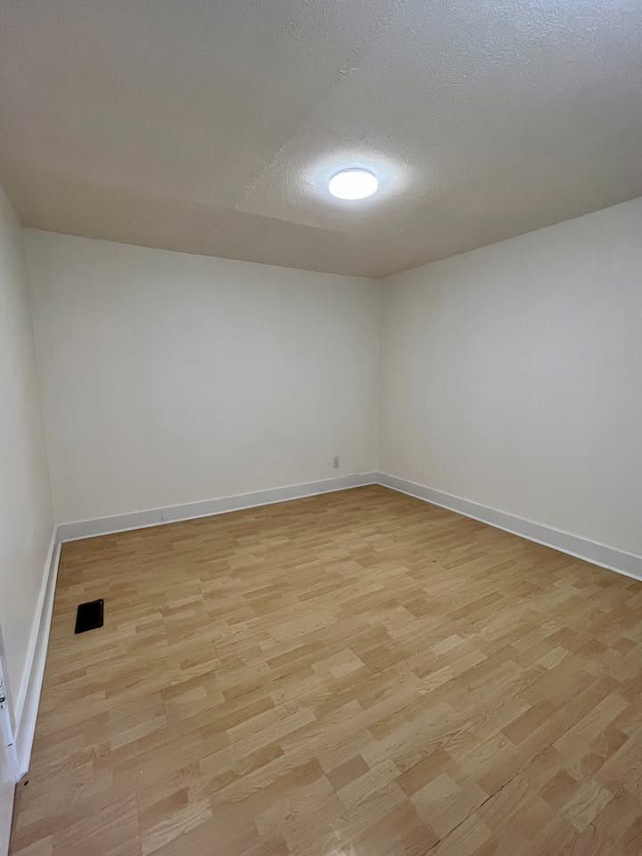 An empty room with hardwood floors and white walls.