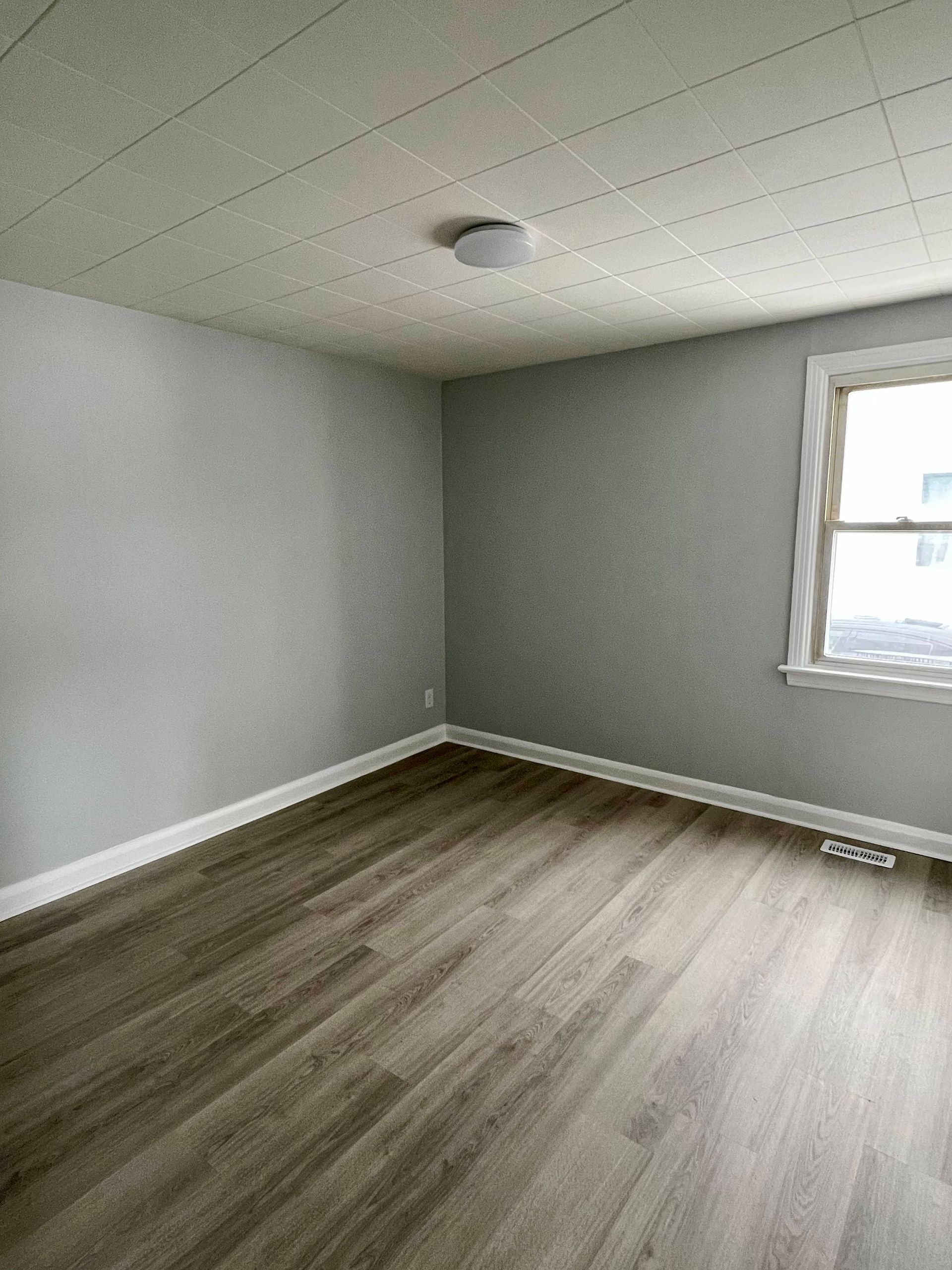 An empty room with hardwood floors and a window.