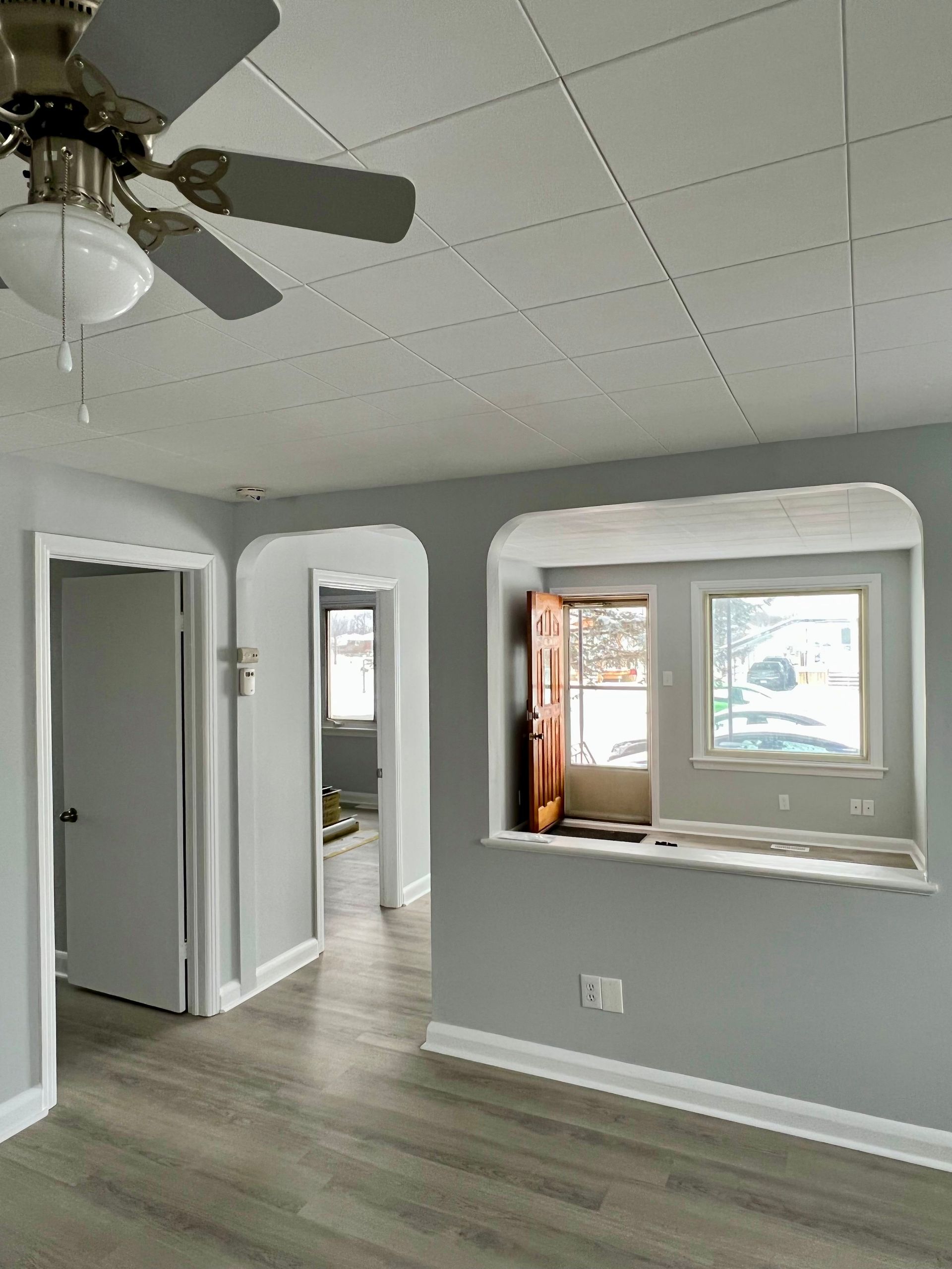 A living room with a ceiling fan and a window.
