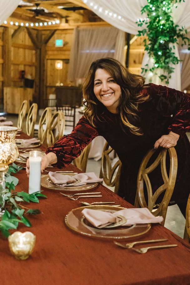 A Woman Is Standing Next to a Table Set for a Wedding Reception by Wedding Planner Nashville