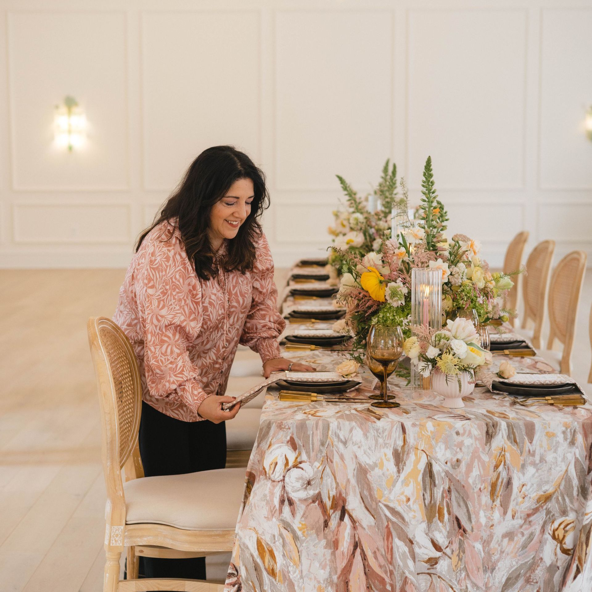 A Woman Is Standing Next to a Table Set for a Wedding Reception by Wedding Planner Nashville