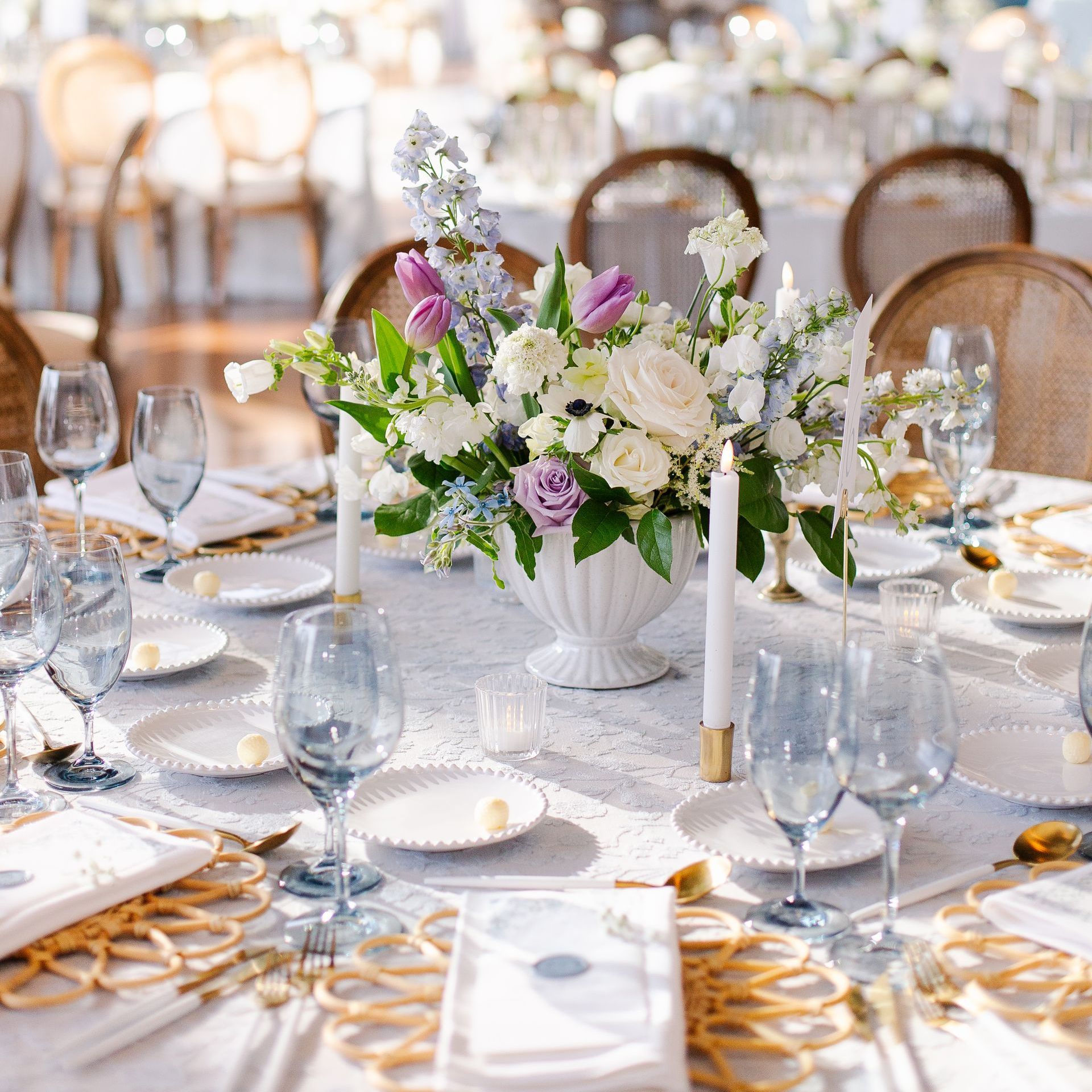 A table set for a wedding reception with a vase of flowers on it.