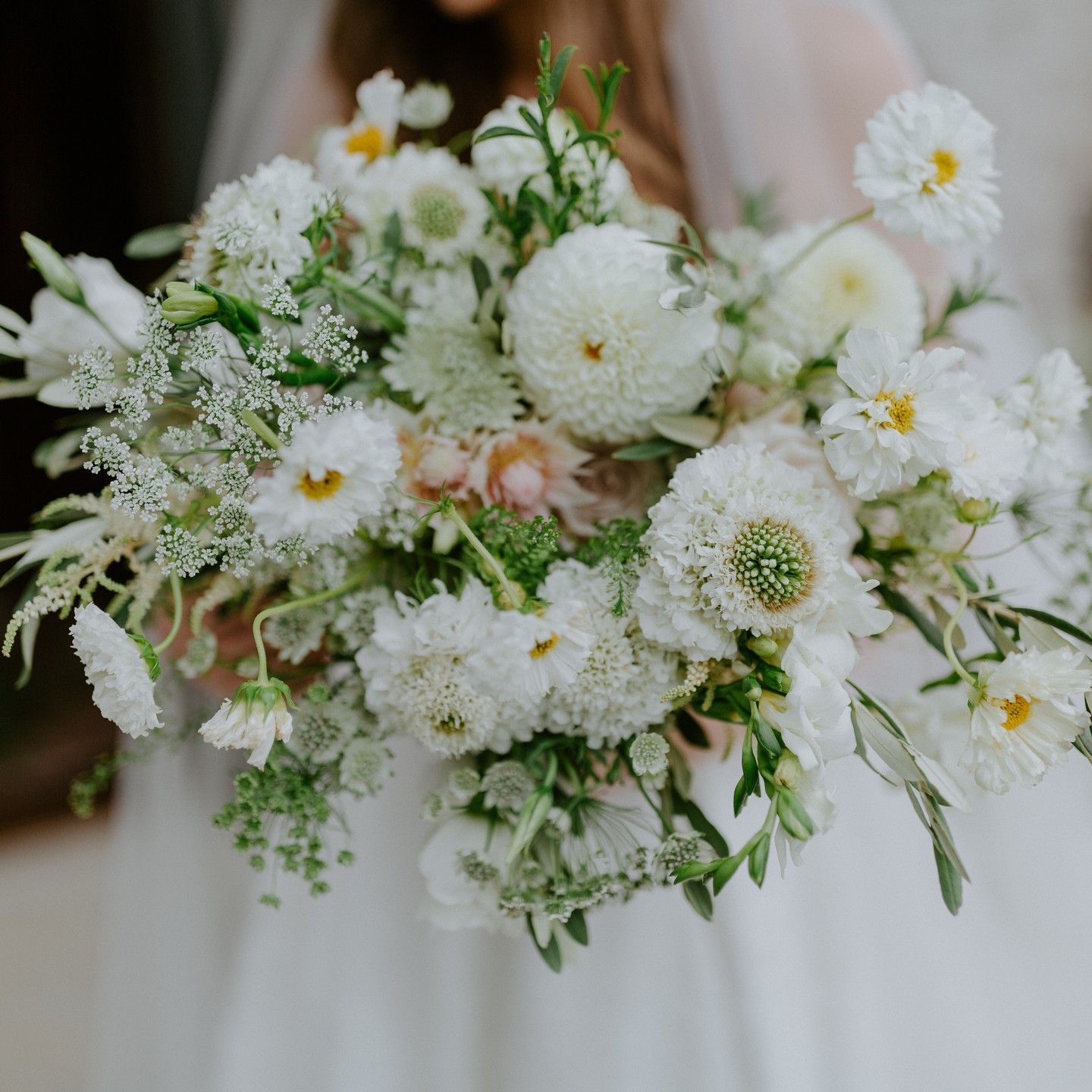 Wedding cake with flowers and leaves on it is sitting on a table by Wedding Planner Nashville