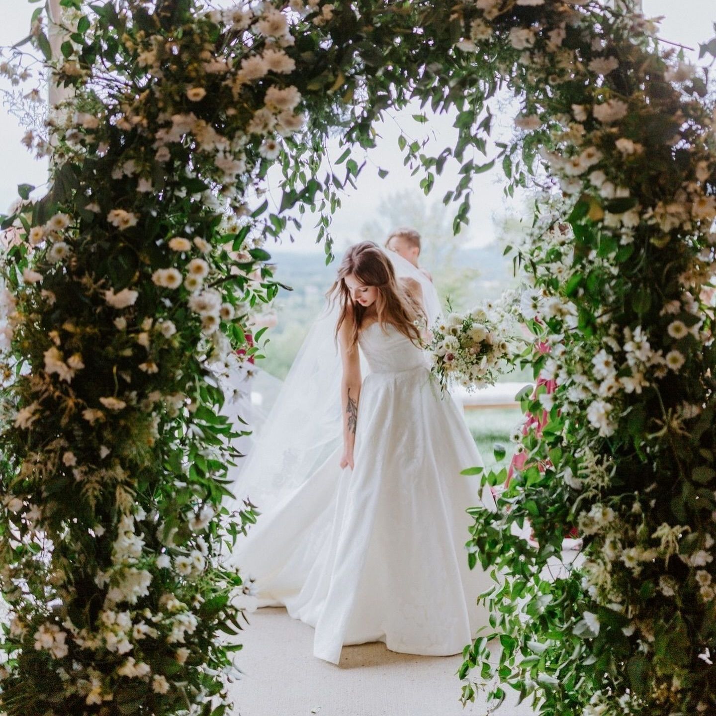 Bride in a wedding dress is standing in a hallway holding a bouquet of flowers by Wedding Planner Nashville