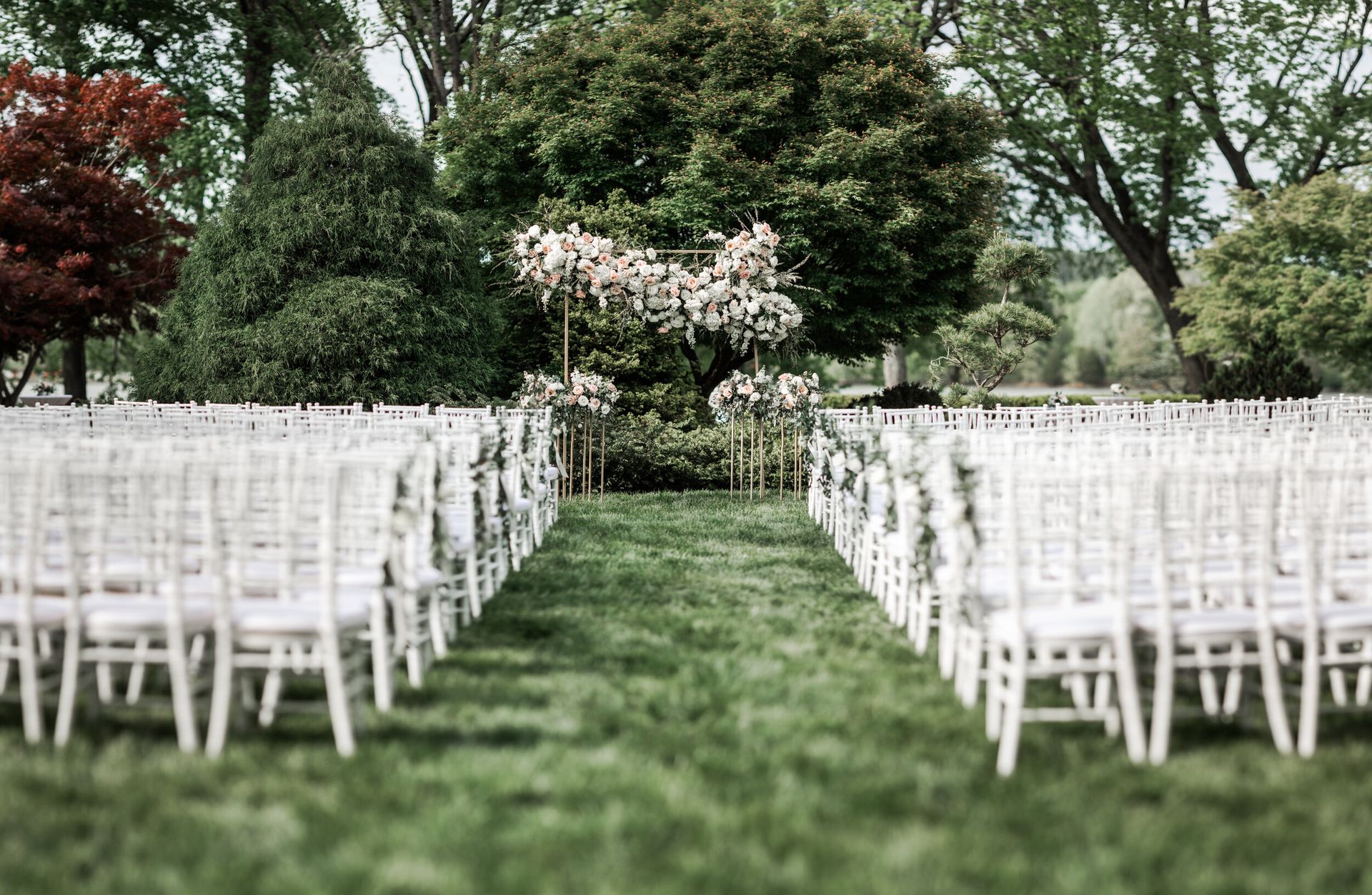 Row of white chairs are lined up in a grassy field for a wedding ceremony by Wedding Planner Nashville