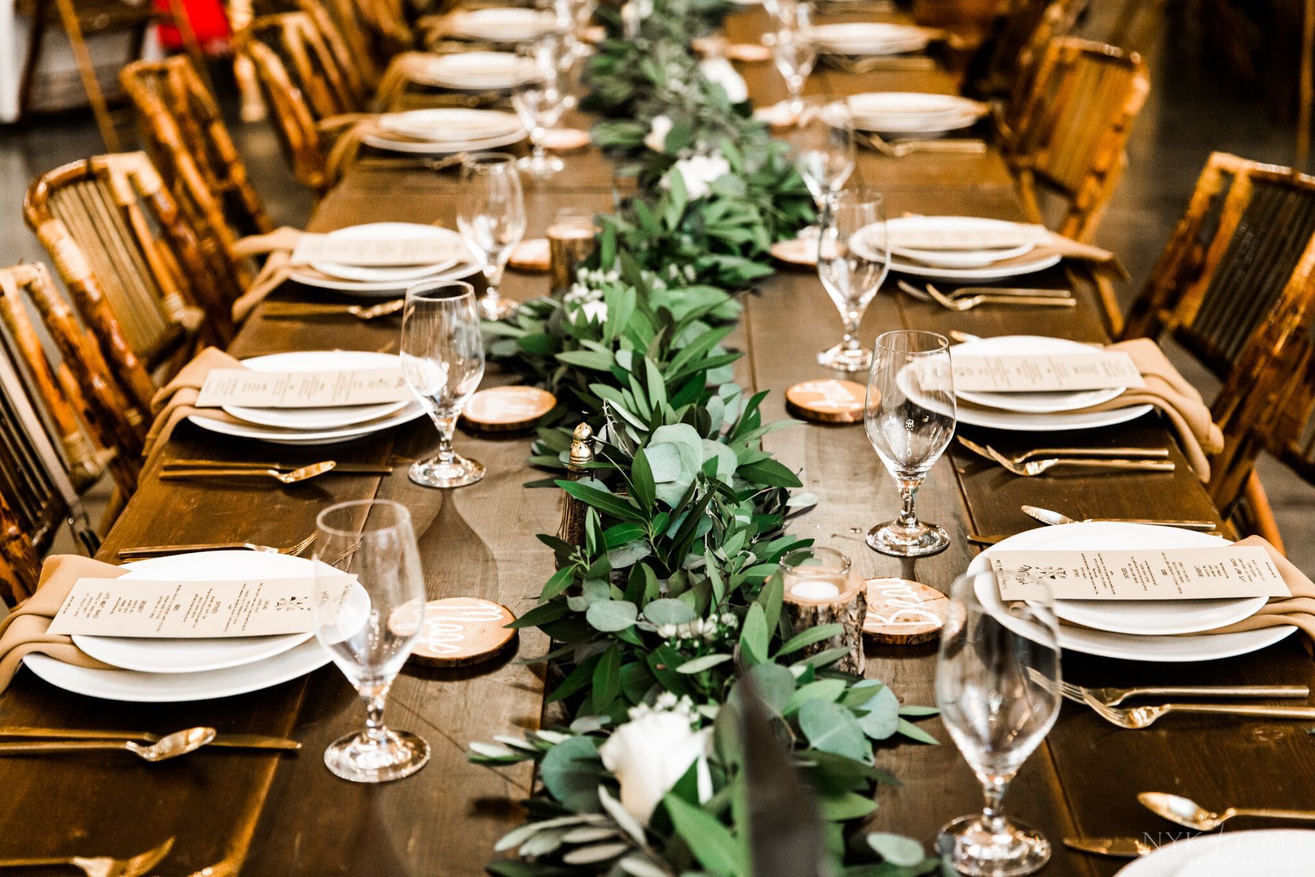 Demi and Lorne’s Wedding long wooden table with plates, glasses, silverware and a garland of greenery by Wedding Planner Nashville
