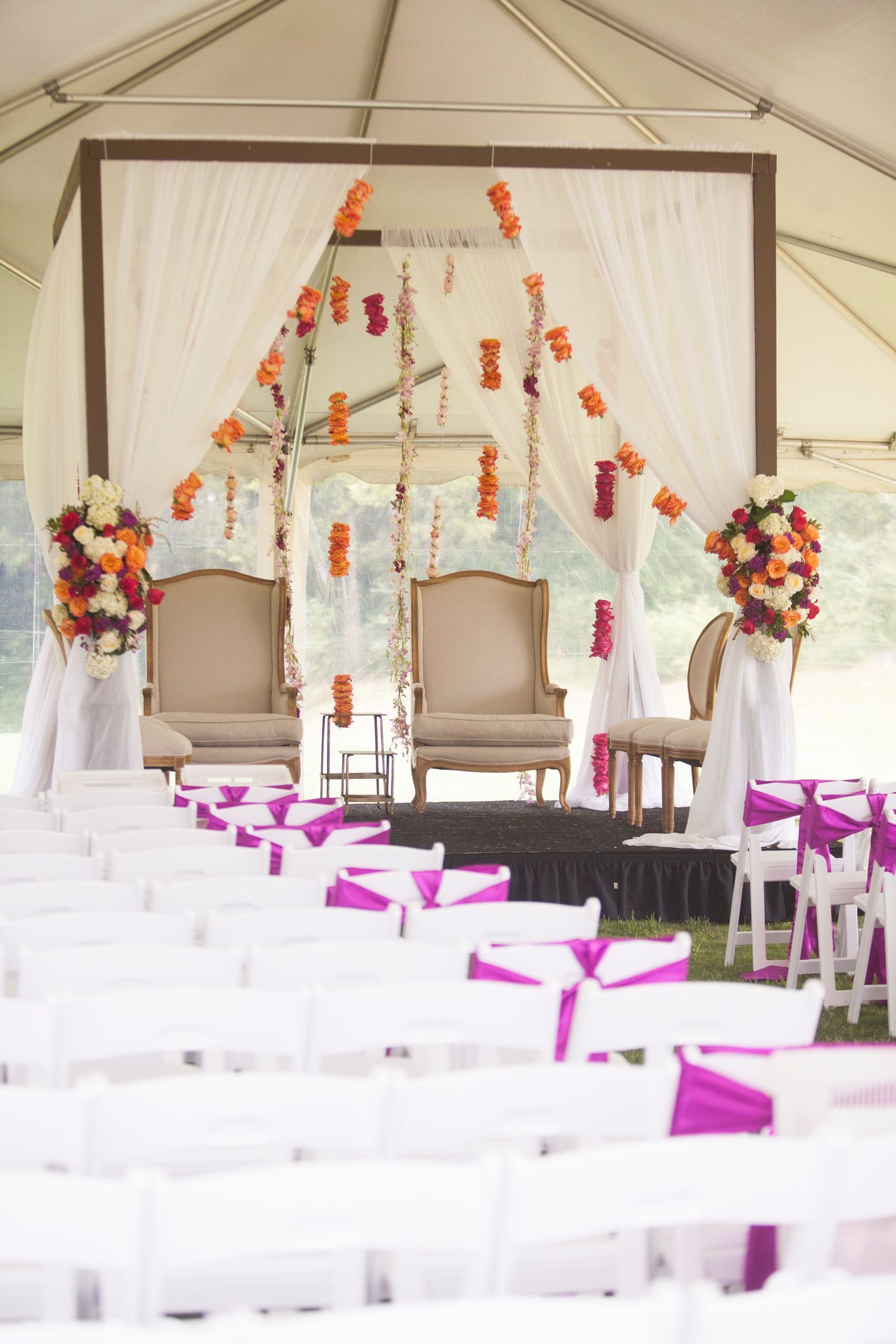 Denise & Nick's Wedding ceremony is taking place under a tent with white chairs and purple sashes by Wedding Planner Nashville