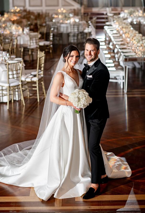 A bride and groom are posing for a picture in a ballroom by Wedding Planner Nashville