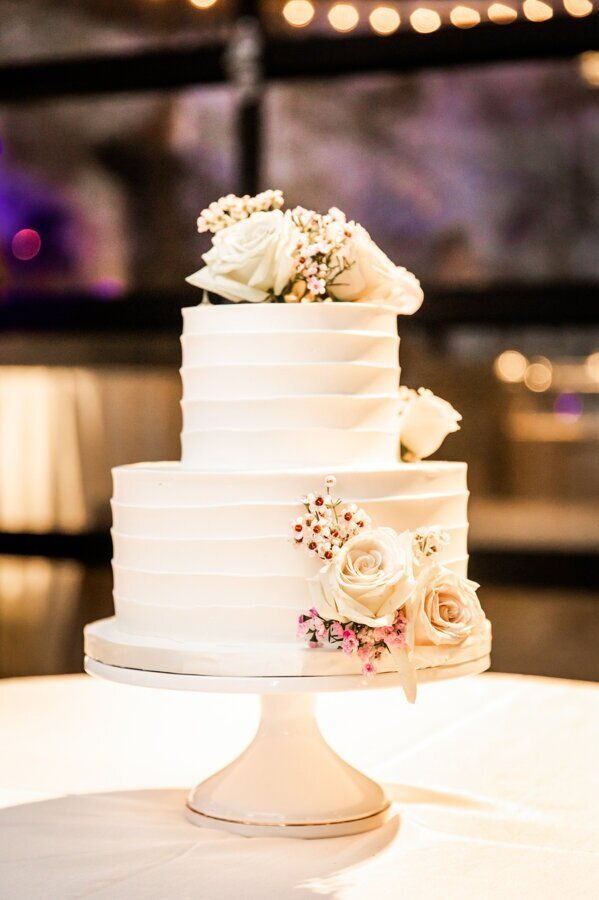 Micro Weddings white cake with white roses on top is sitting on a white table by Wedding Planner Nashville