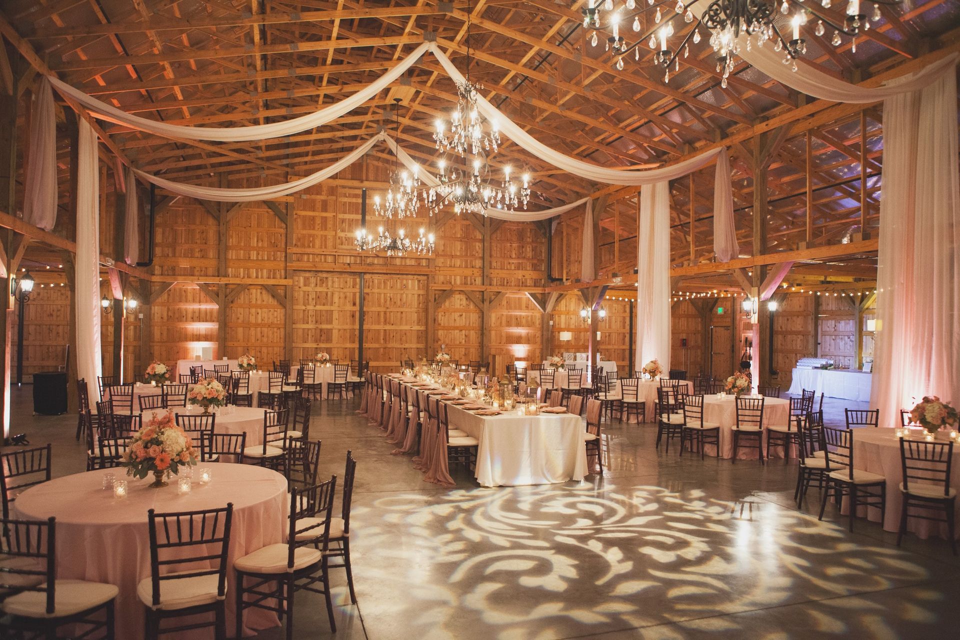 Rachel and Richard's Wedding reception in large barn filled with tables and chairs and a dance floor by Wedding Planner Nashville