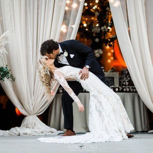 Bride and groom are kissing in front of a white curtain by Wedding Planner Nashville