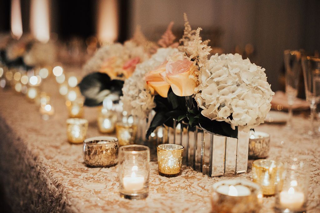 Long table with gold themed candles and flowers on it by Wedding Planner Nashville