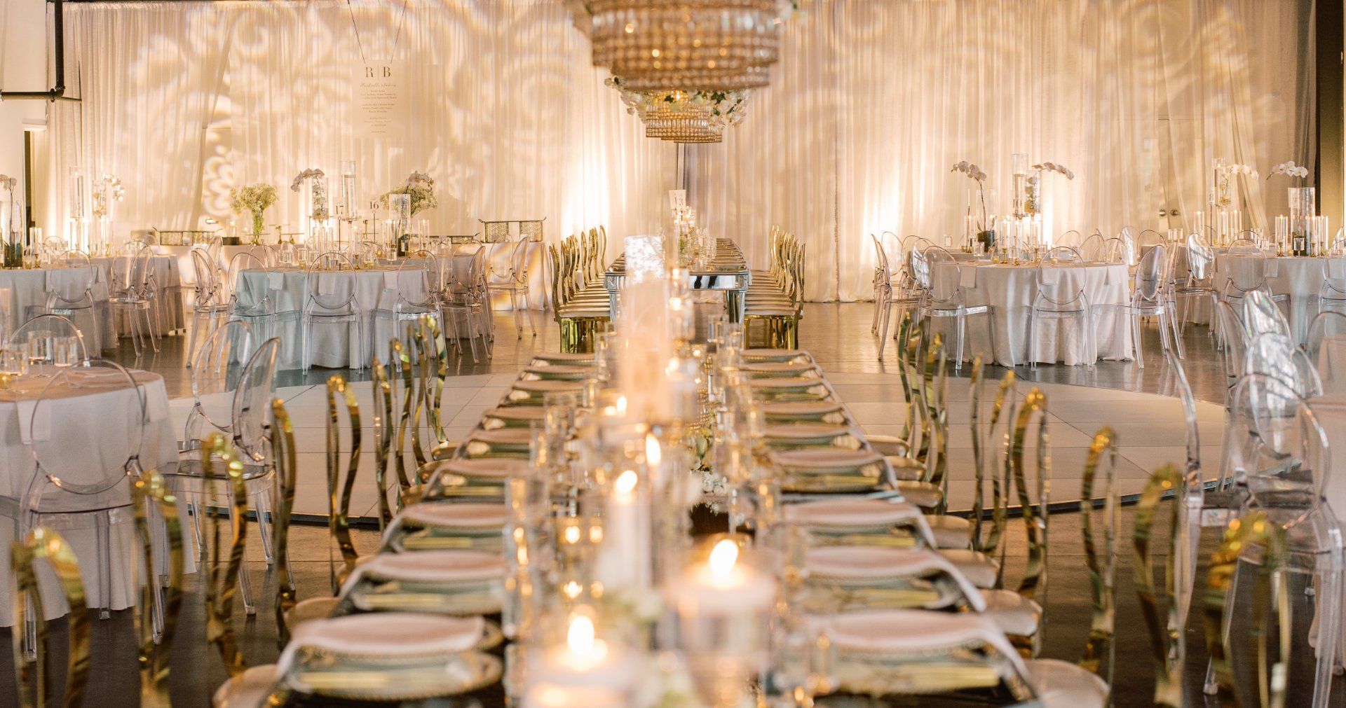 A long table with plates and candles in a large room by Wedding Planner Nashville