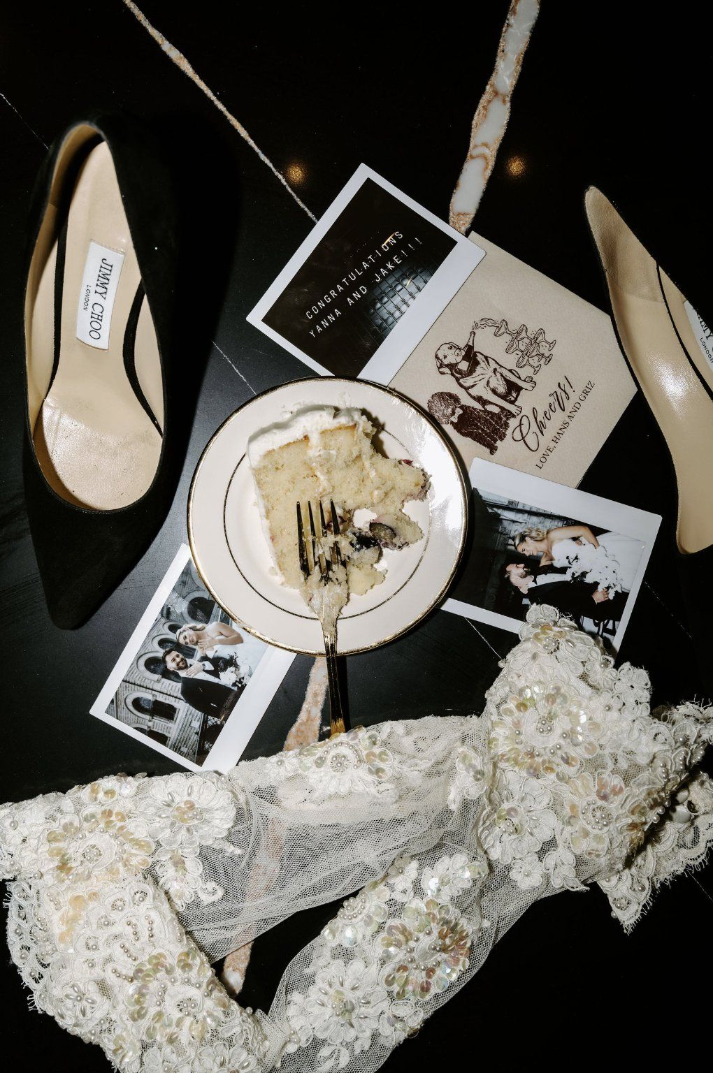 Black heels, a slice of cake, wedding photos, and lace gloves on a black surface by Luxury Wedding Planners in Nashville, TN